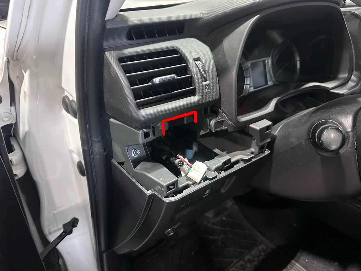 Car interior with open glove compartment showing wiring and components.