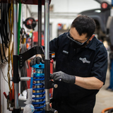 Technician setting shock assembly in a garage.