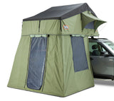 A green tent and annex extension with a black top designed for rooftop attachment, pictured with a vehicle.