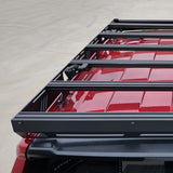Black roof rack system on a red vehicle with a light gray background