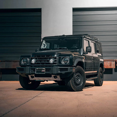 Black off-road vehicle parked in front of a building with a garage door.