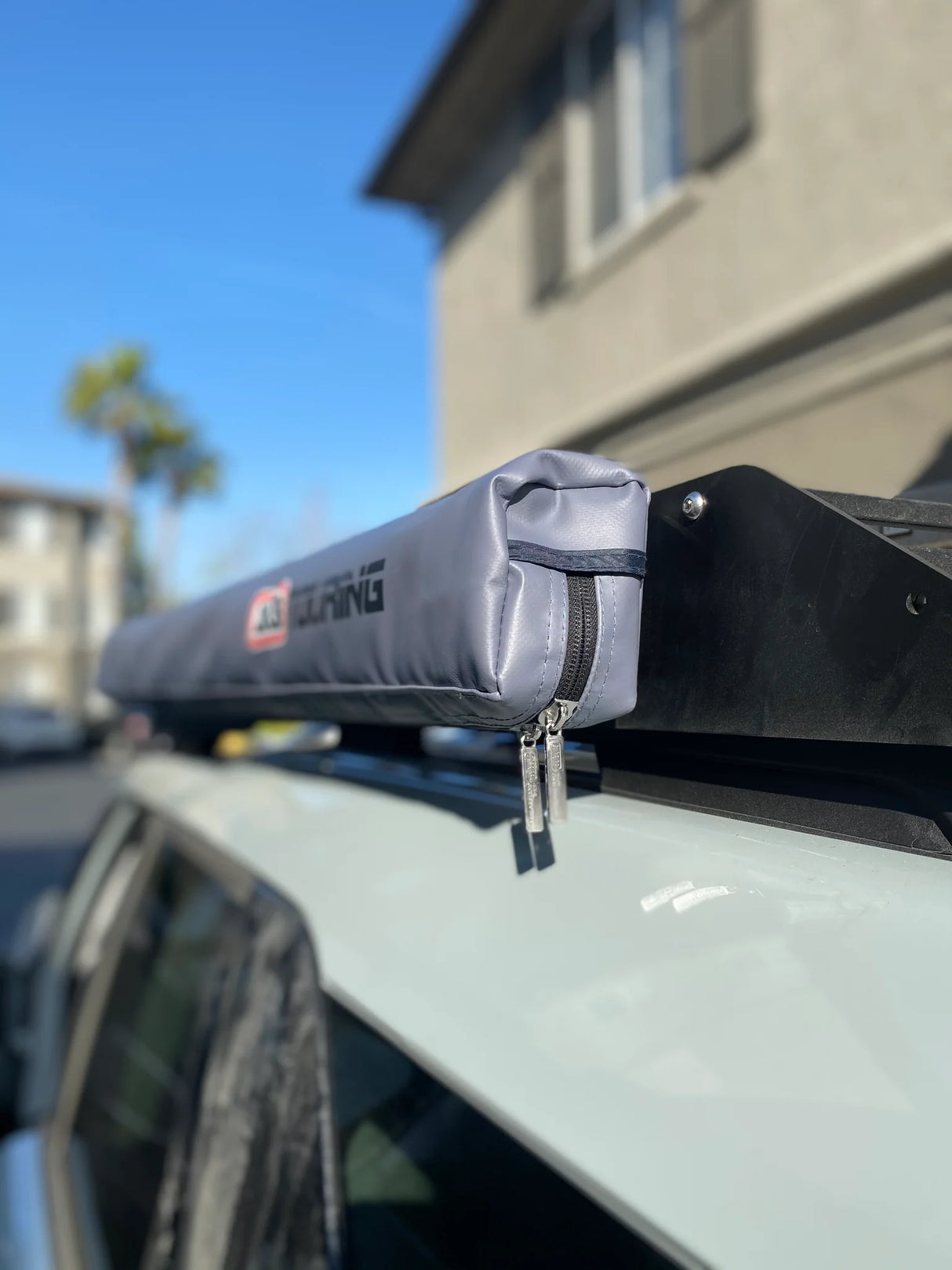 Roof rack with a gray cover on a car, brand 'Alpine' visible