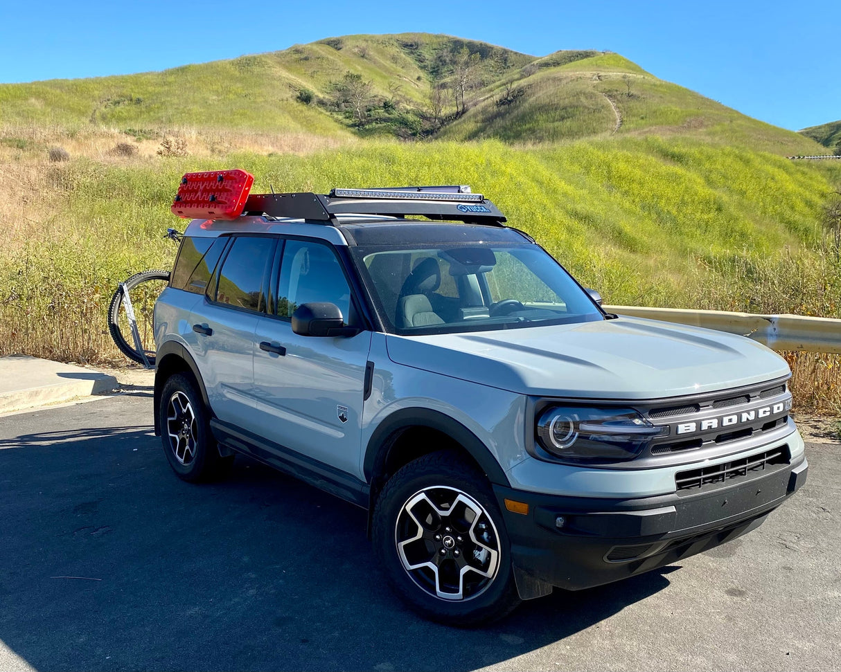 Ford Bronco SUV with roof rack and red light on a scenic road
