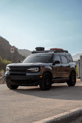 Black SUV parked on a road with mountains in the background