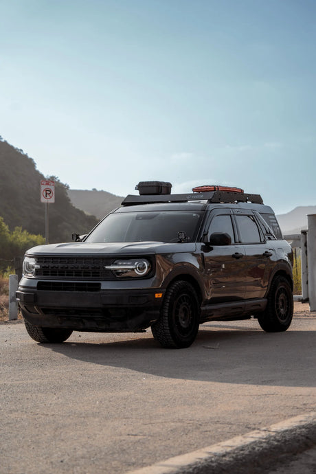 Black SUV parked on a road with mountains in the background