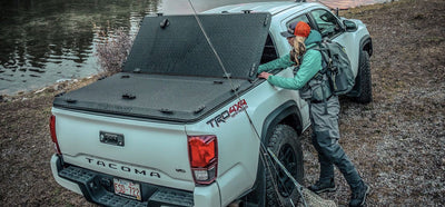 Woman popping a DiamondBack HD tonneau cover open to get fishing gear